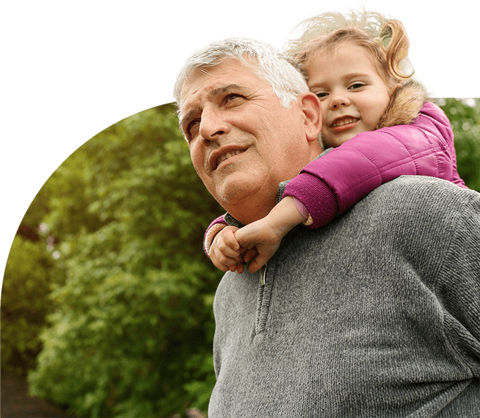 Grandfather on a walk with his granddaughter on his shoulders.