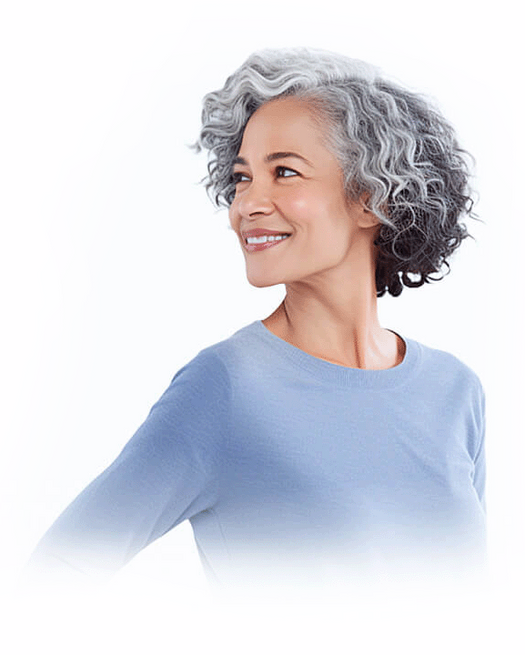 Woman with grey wavy hair in a blue sweater looking left, smiling.