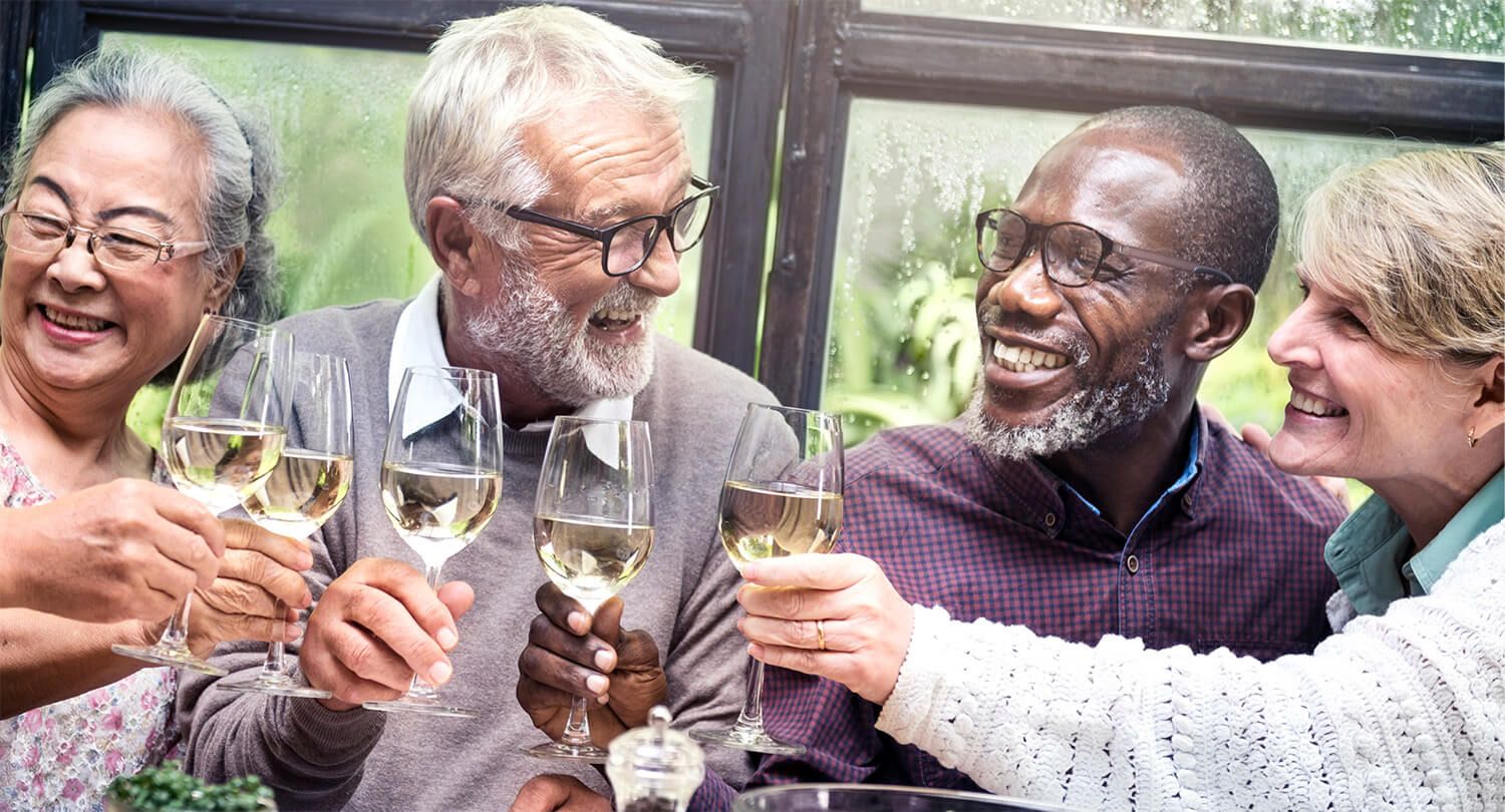 Group of seniors laughing and toasting glasses of wine.