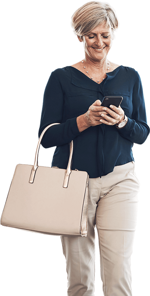 Woman walking smiling down at her cell phone.