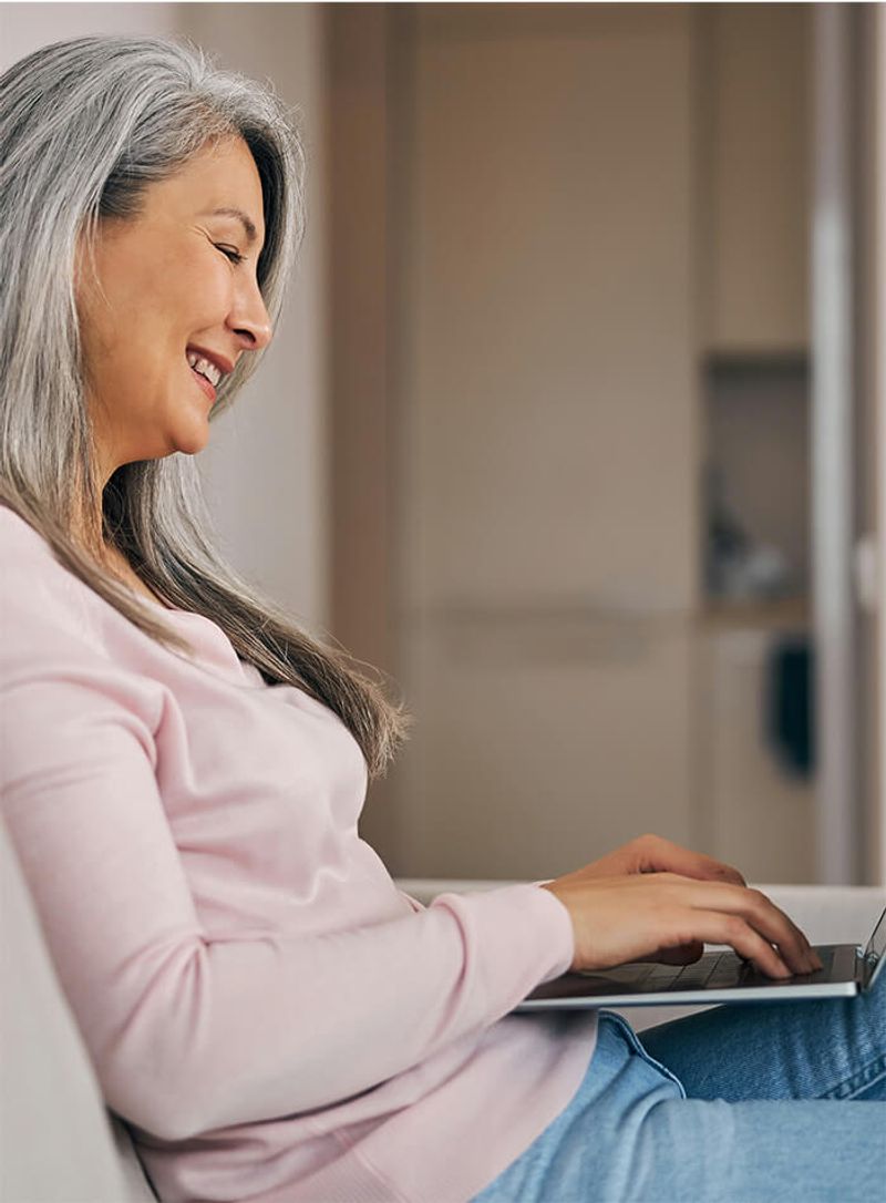 Woman on couch with laptop searching for Medicare plans on Healthpilot.