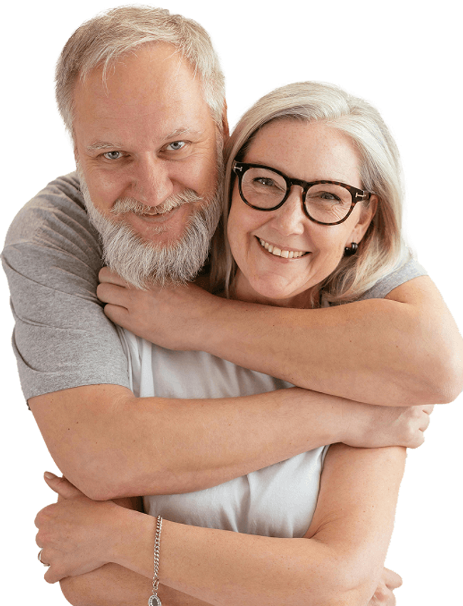 Mature couple smiling with the mans arms wrapped around the woman.